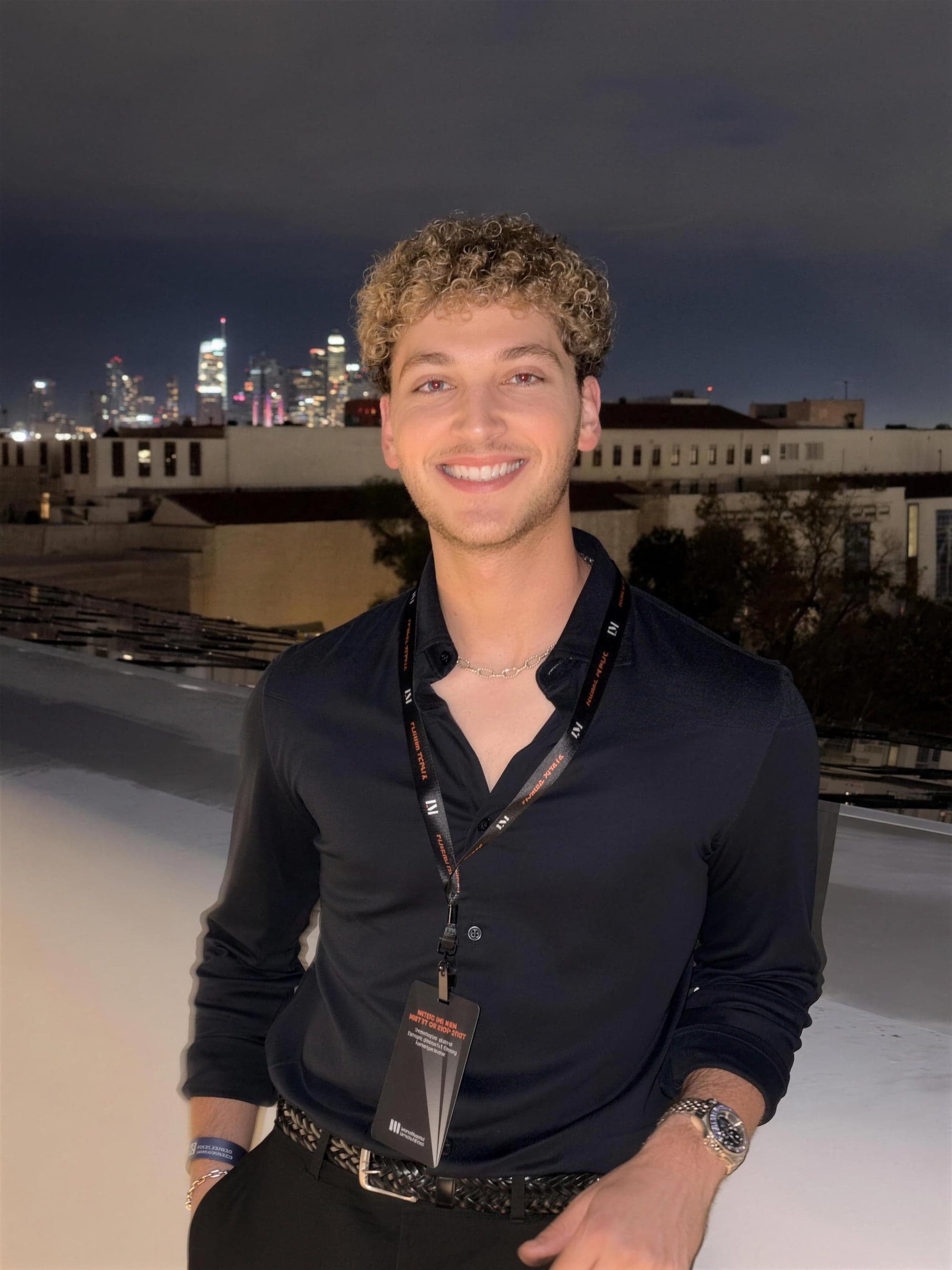 Josh Karasik on a rooftop with the Los Angeles skyline at night