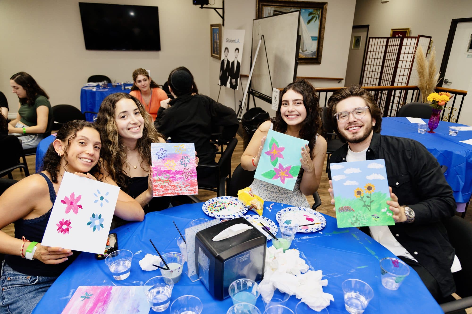 Friends showing off their paintings at a ShalomLA paint night